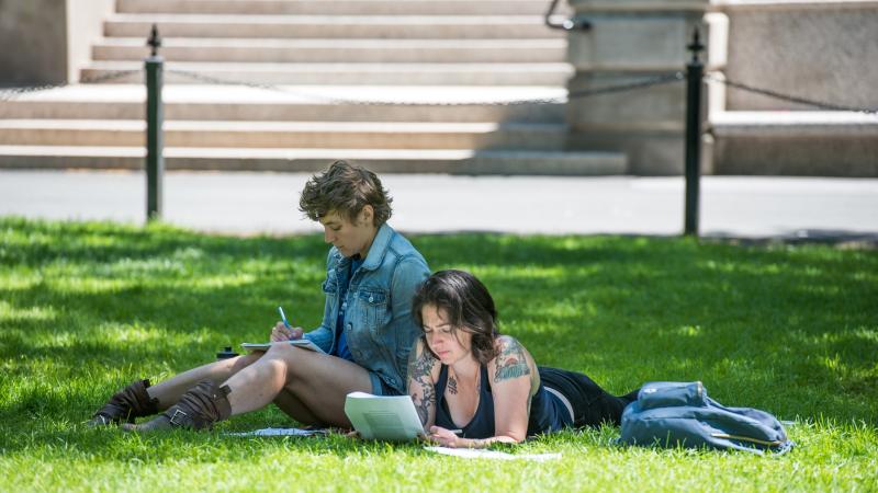 Two students sit outside and study.