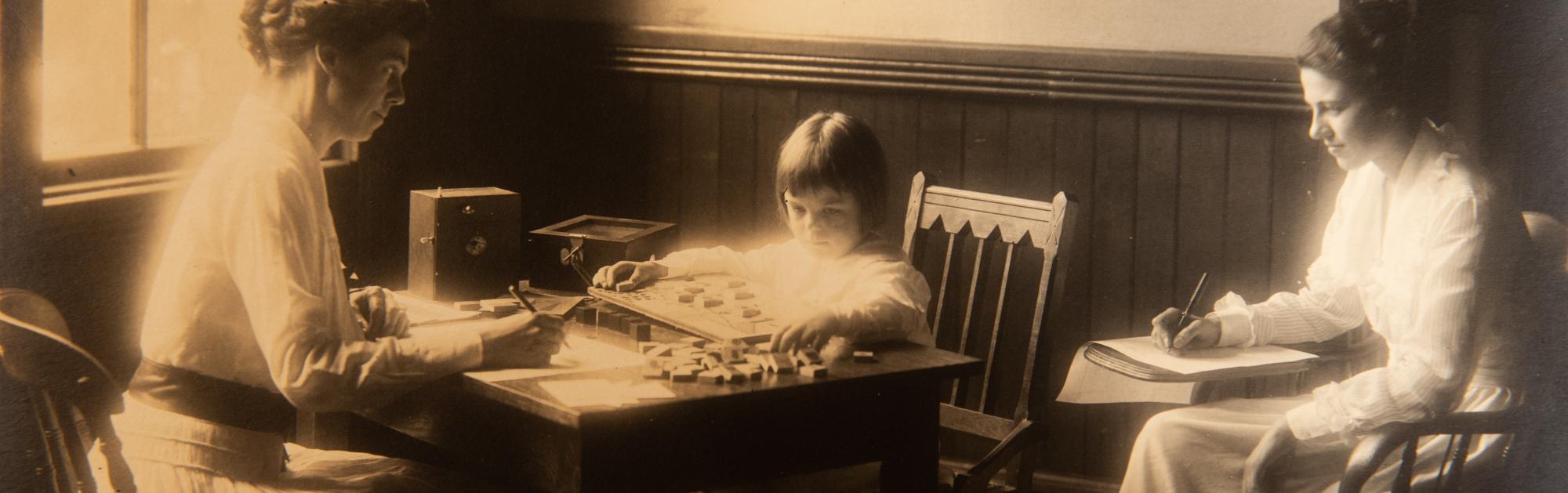 A historical black and white photo of two social workers working with a young child. One woman is observing and taking notes.
