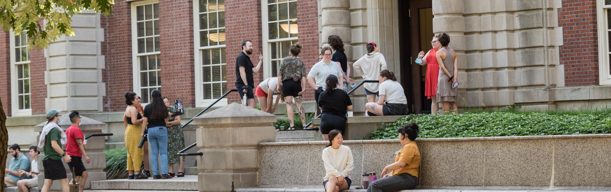 A group of students stands on the steps of Seelye Hall during the summer. 