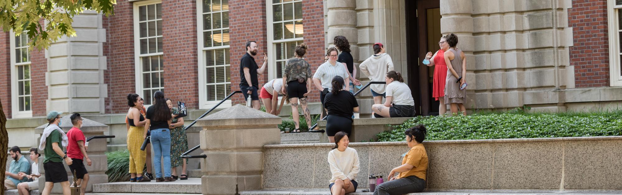 A group of students stands on the steps of Seelye Hall during the summer.